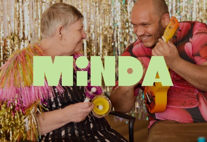 Minda campaign artwork featuring two people celebrating together with bold green Minda branding.