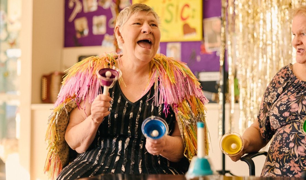 Person celebrating with colourful bells and party decorations in Minda campaign photography.