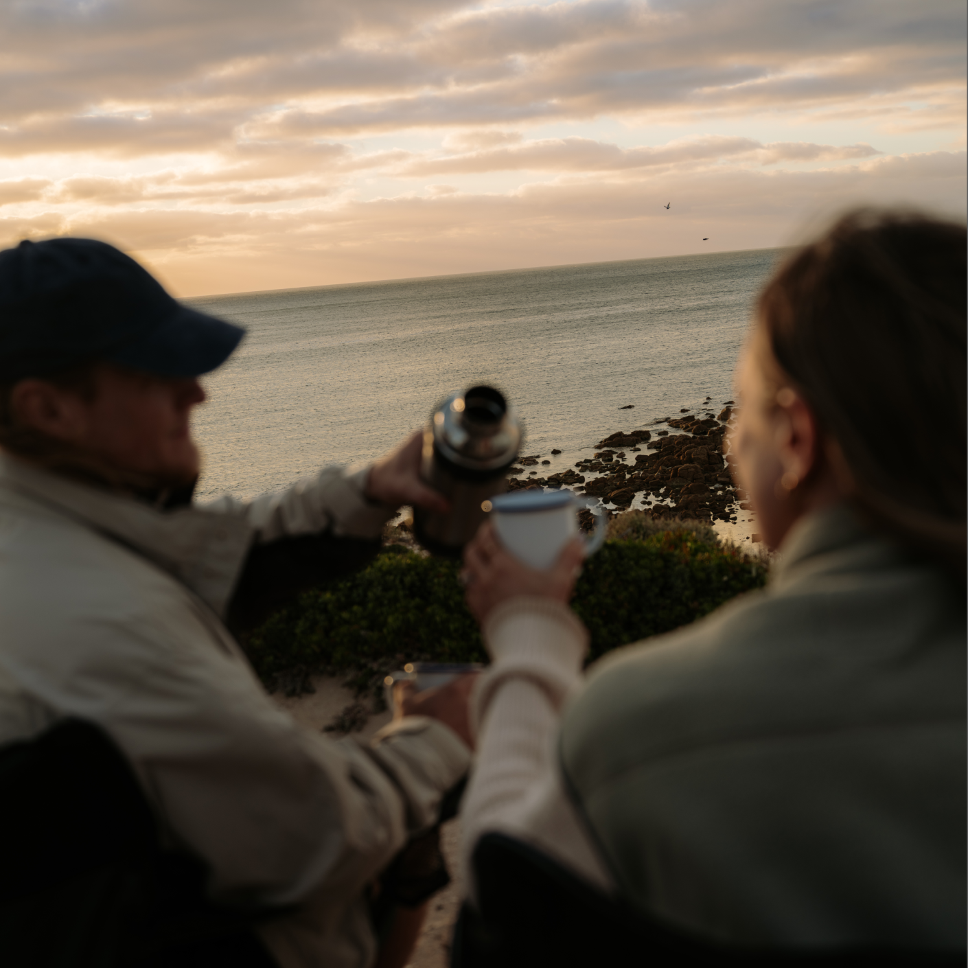 People enjoying a cup of tea while overlooking the South Australian coastline at sunset.