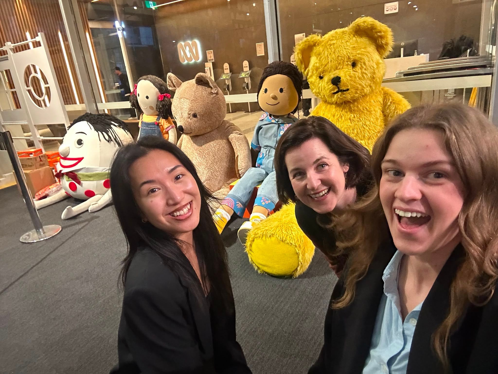 Raph, Kate and Rachael waiting in a line for Gruen surrounding by giant play school plush characters