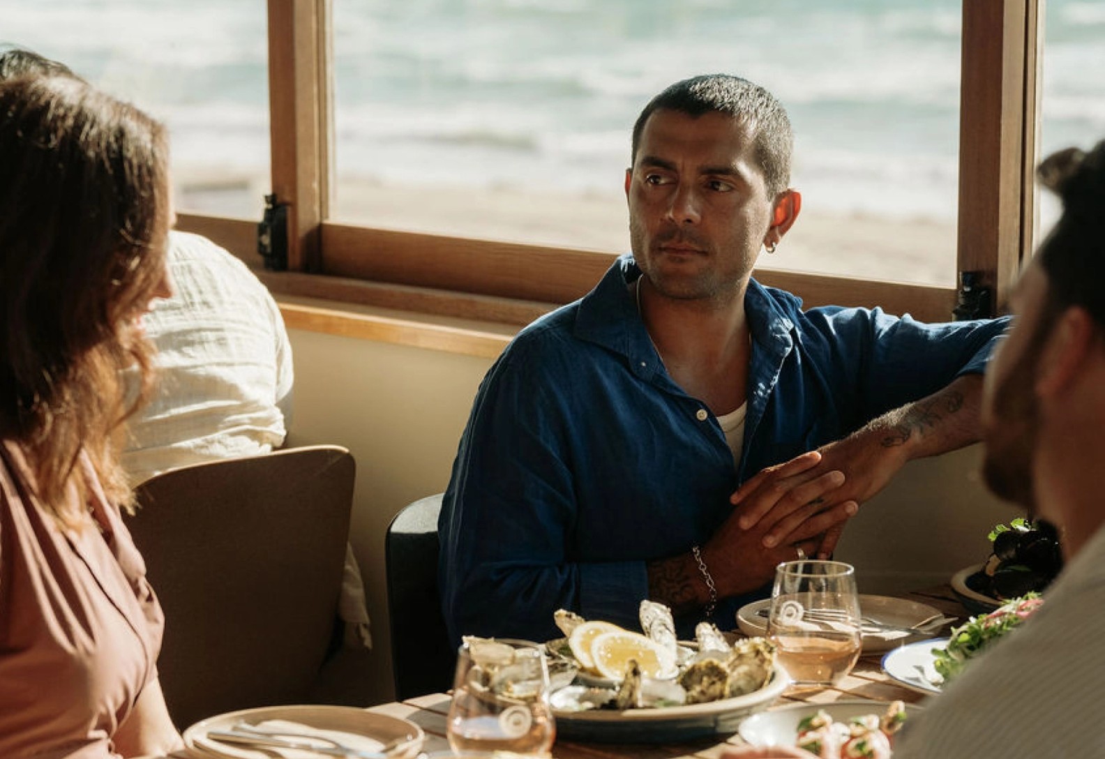 People eating and drinking at a restaurant with the ocean in the background