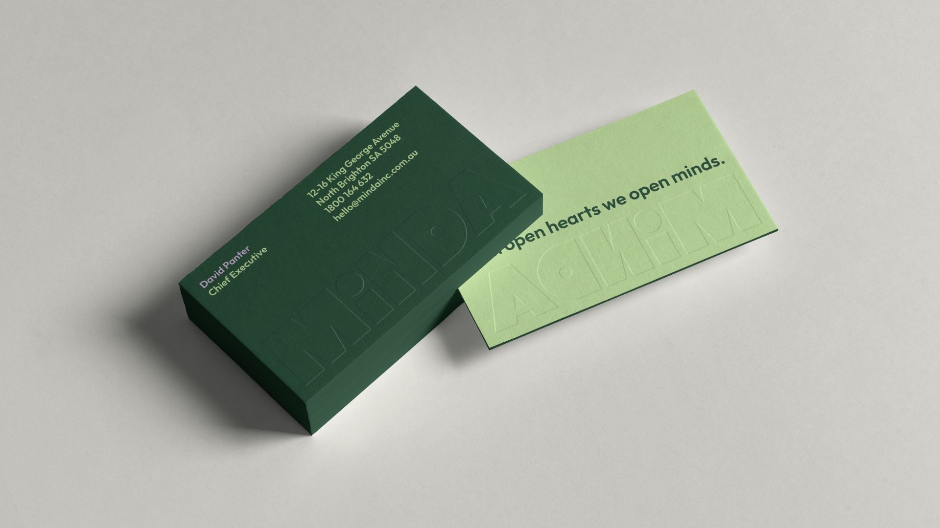 Minda branded business cards featuring the green visual identity and inclusive messaging.