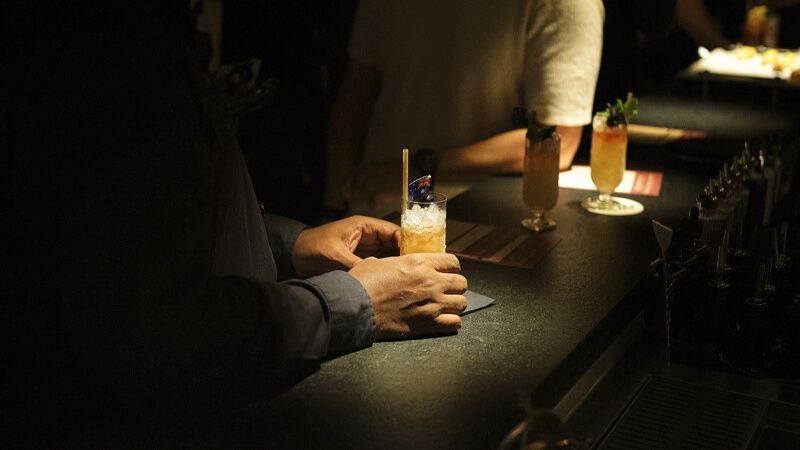 close up of person holding a drink at a bar