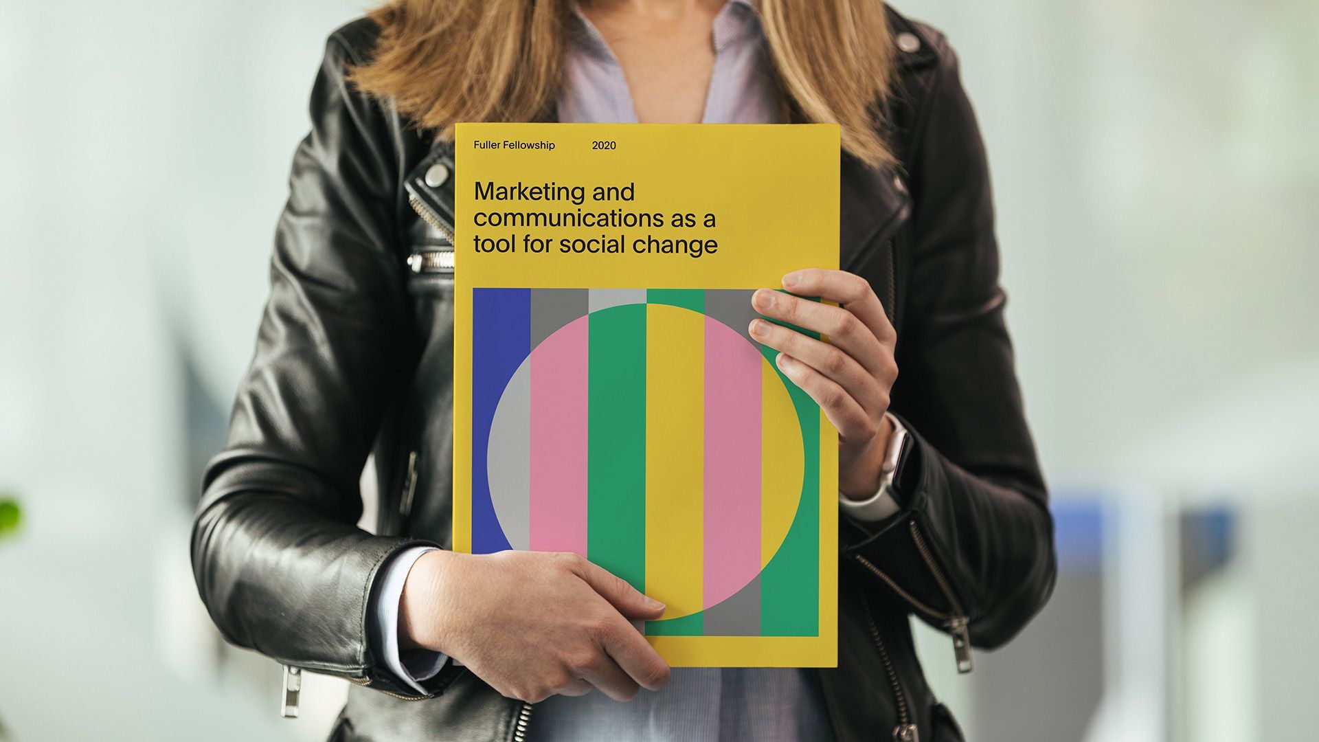A person holding up a marketing and communications booklet