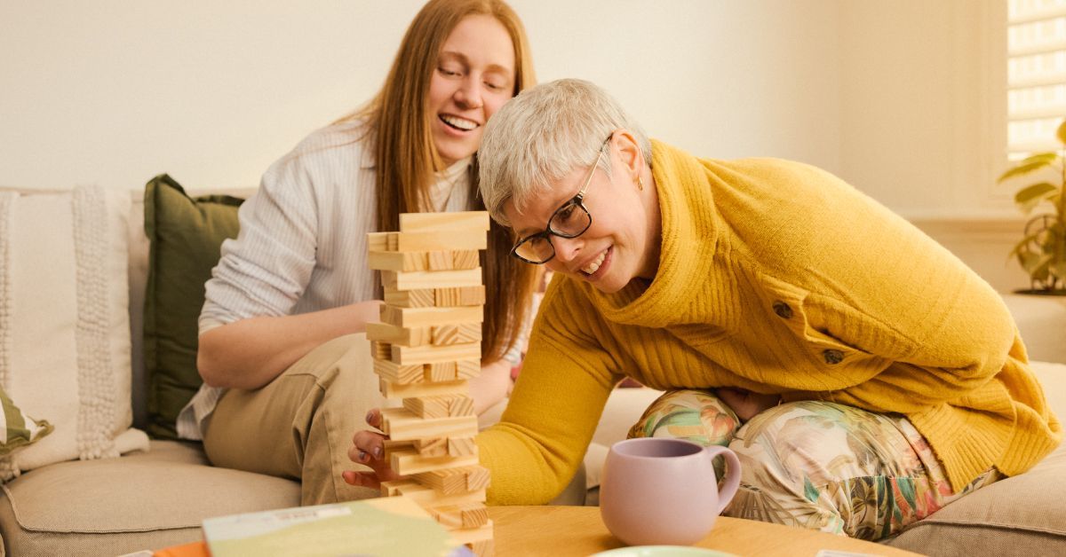 Two people laughing while playing jenga.