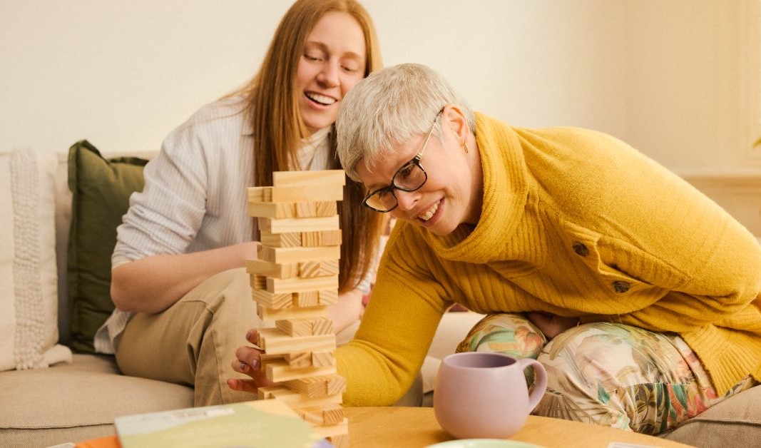 Two people laughing while playing jenga.