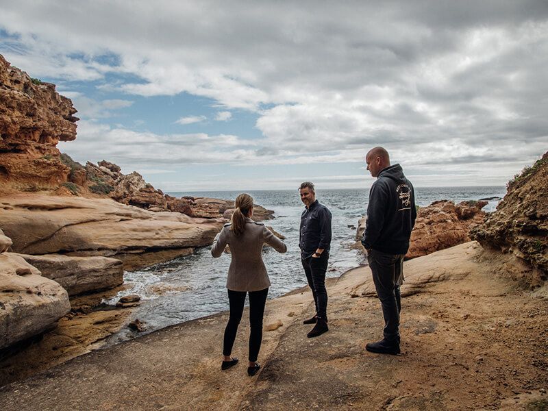 People standing on rocks by the beach