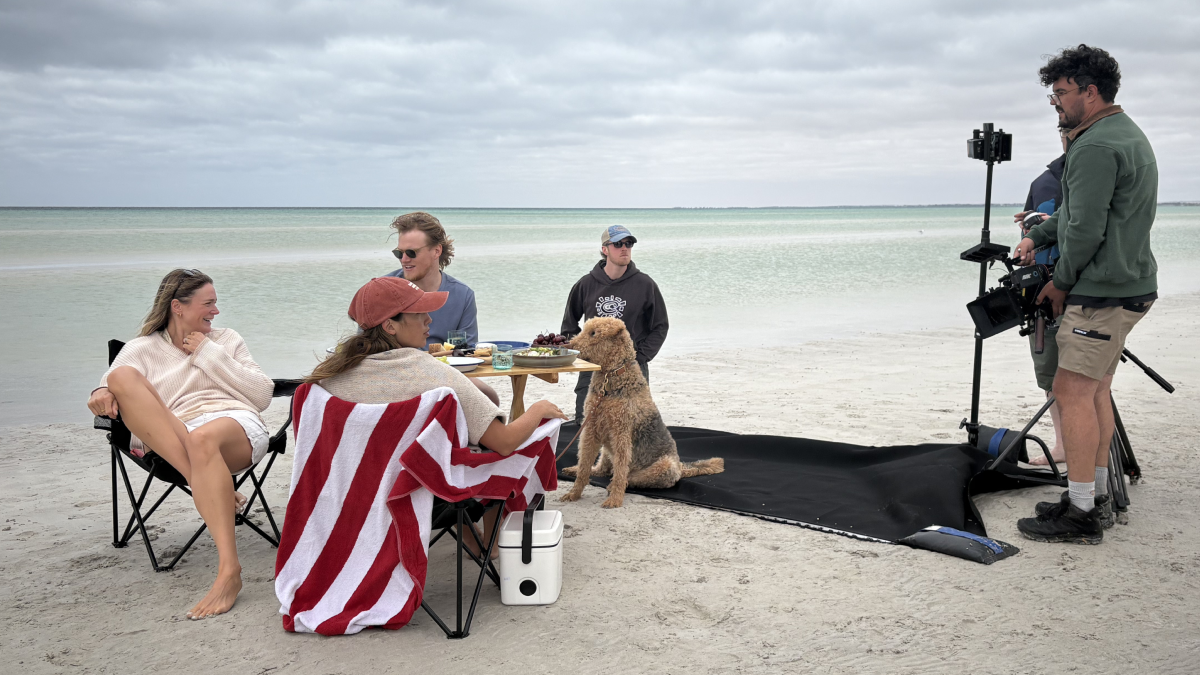 People and a labradoodle dog enjoying a beachside meal on the South Australian coast being filmed by the Fuller crew