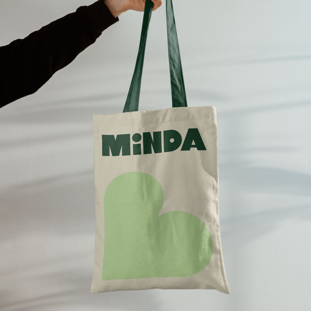 Minda branded tote bag featuring the green visual identity.