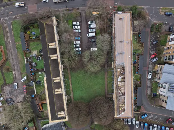 Top-down drone view of two scaffolded residential blocks at Fernside Close, with one roof stripped and one adjacent block under scaffold access.