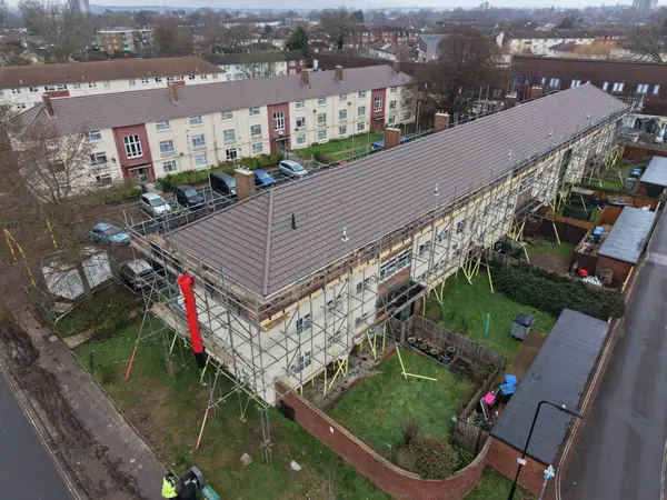 Aerial progress photograph showing renewed roof tiles, scaffold walkways and the surrounding Honister Close estate.