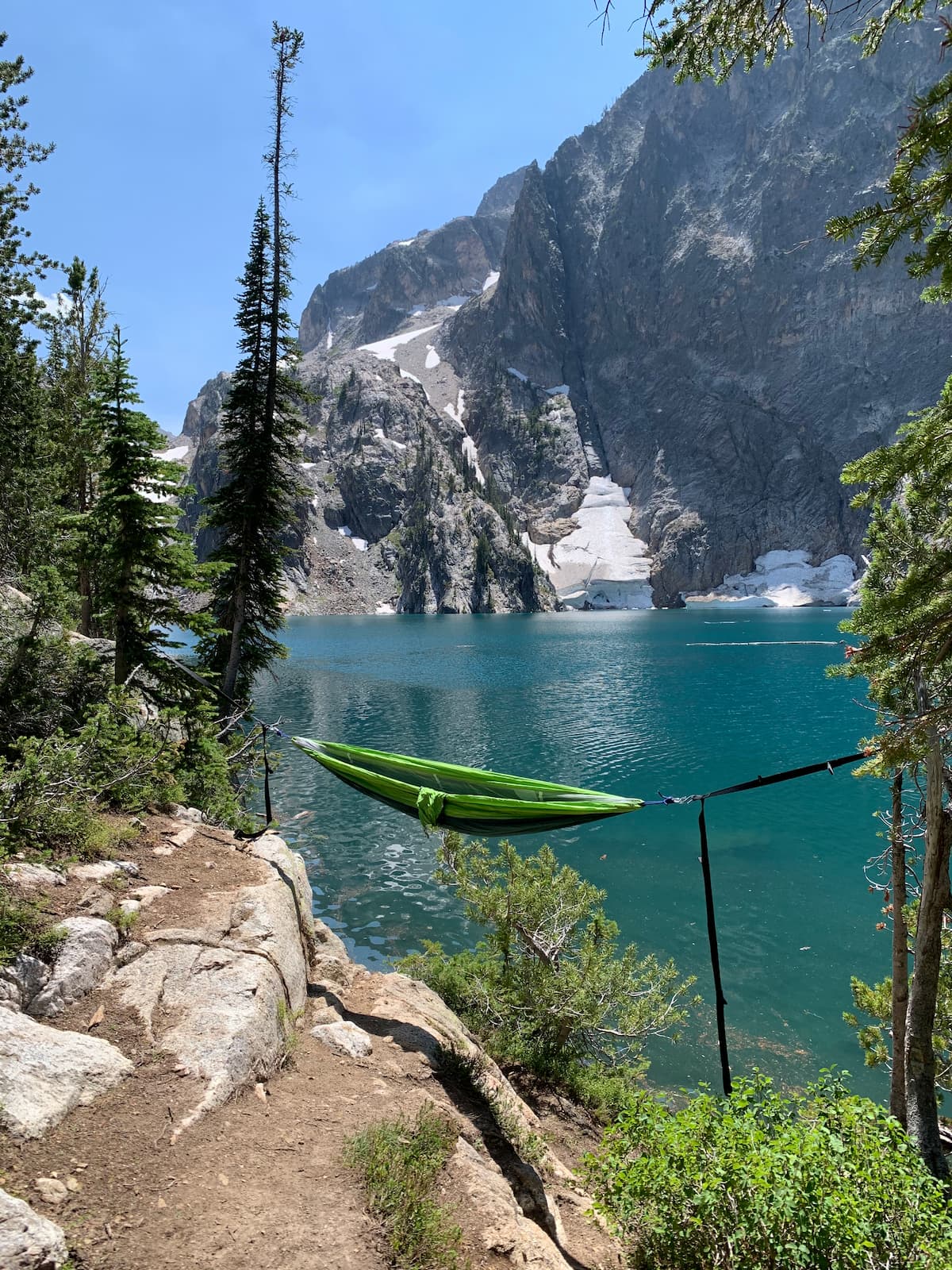 A picture of a hammock in front of a blue lake