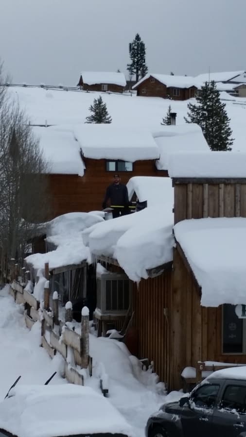Man Standing Next to Cabin Covered in Snow | Stanley Chamber