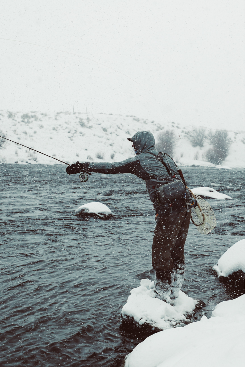 A person fishing in snowy terrain