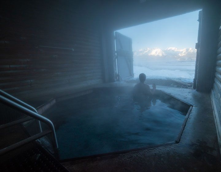 a man soaking in a hot spring with mountains in the background | Stanley, ID