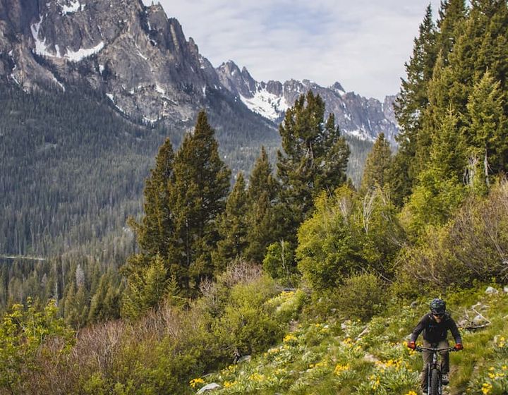 Man biking on a hill with a mountain and a lake in the background