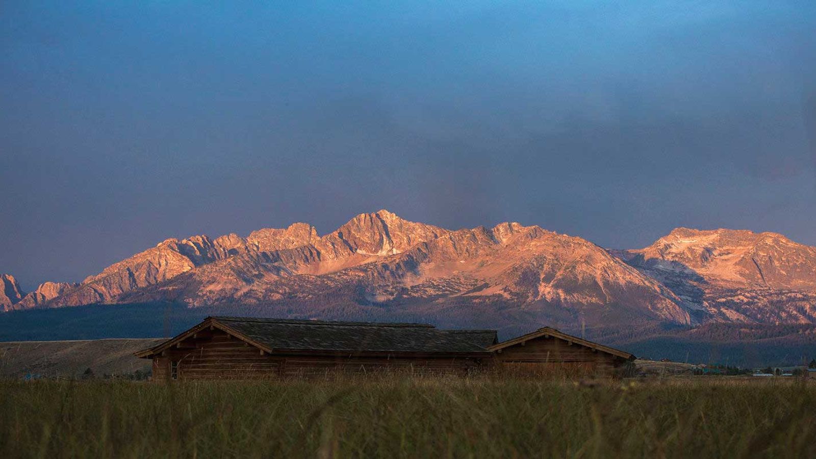Cabin in an open field with the Sawtooth Mountains in the background | Stanley Chamber