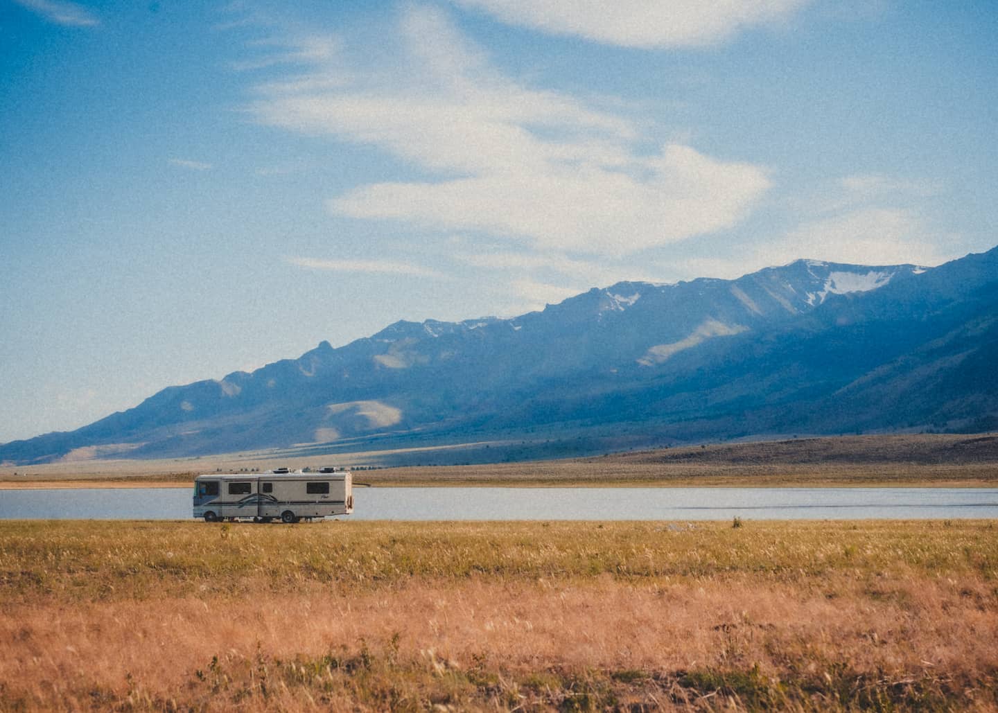 A camper next to a lake in front of mountains