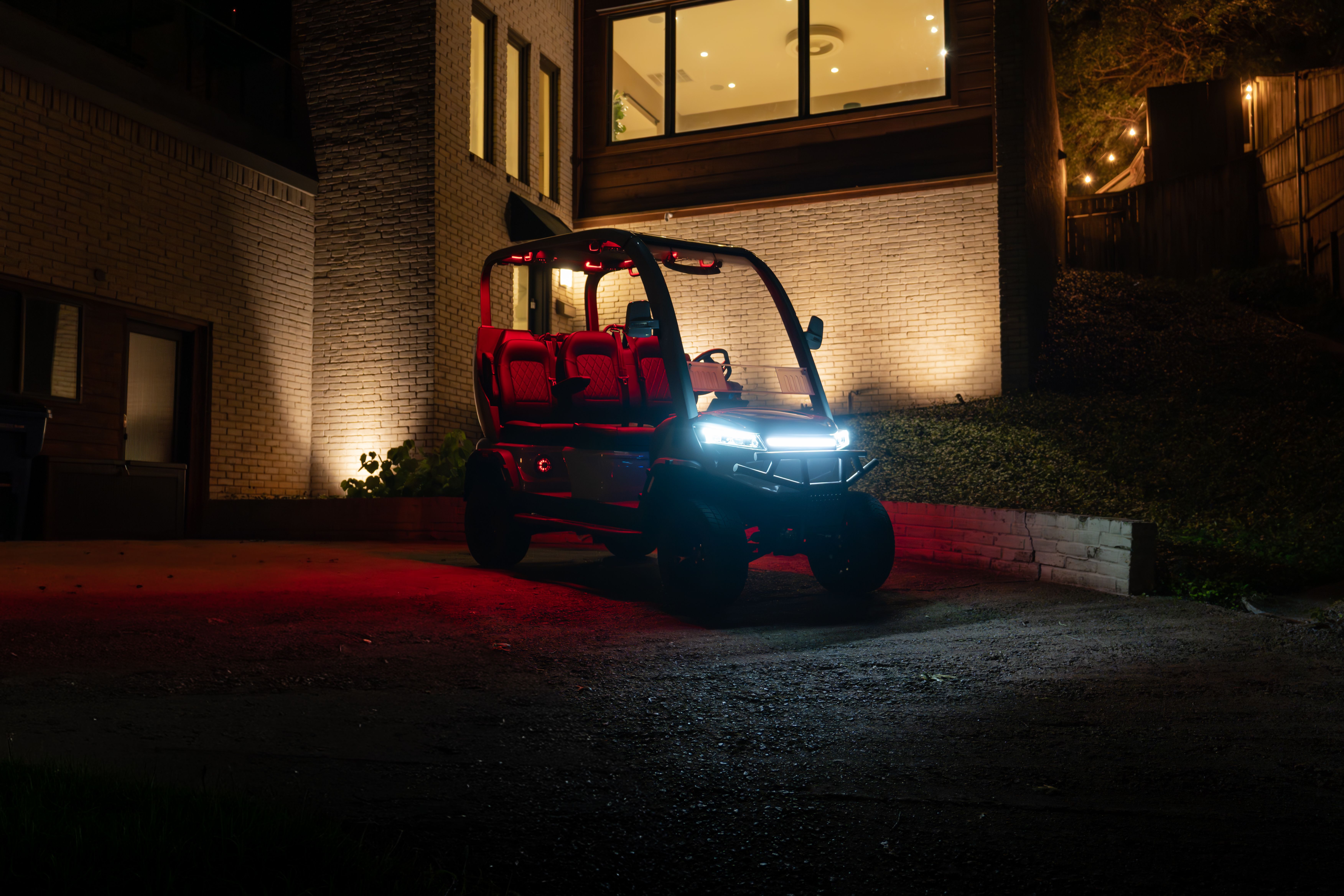 The NIUGT with its LED lighting on, parked in front of a lit house at night