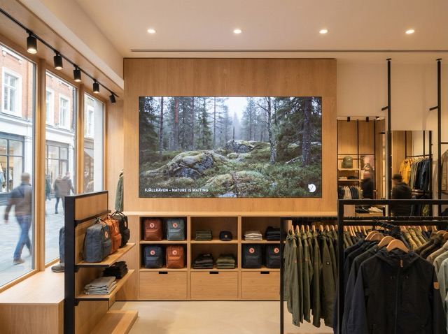 Fine-pitch LED display built into the wall of a retail interior above a product table.