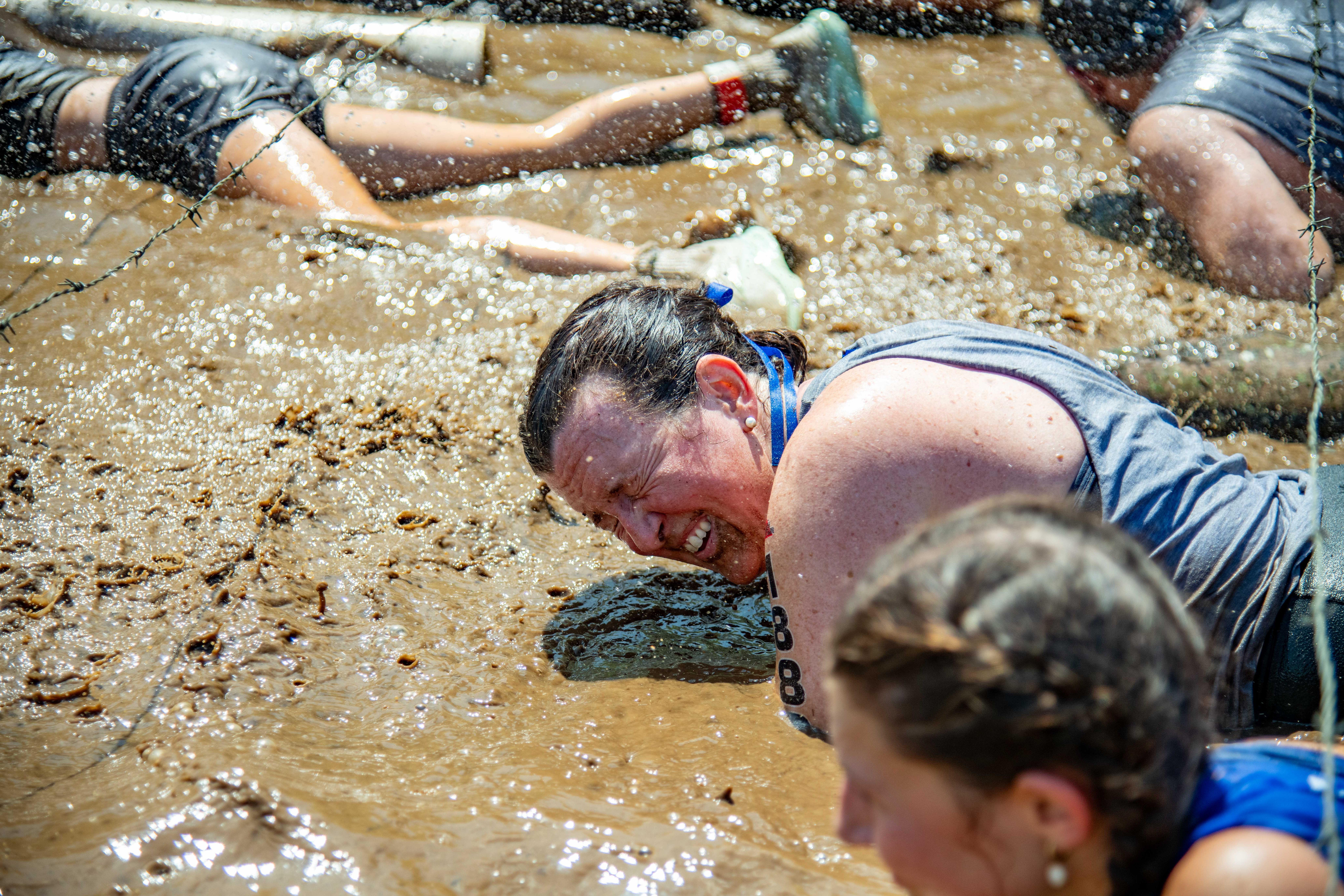A woman closing her eyes in muddy water.