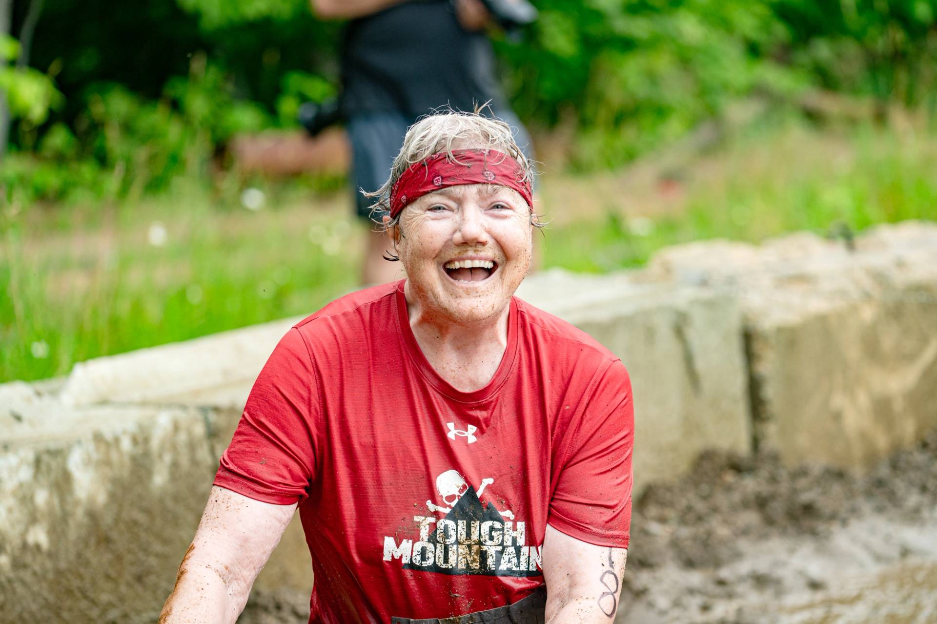 A woman smiling in a mud pit at Sunday River's Tough Mountain Challenge.