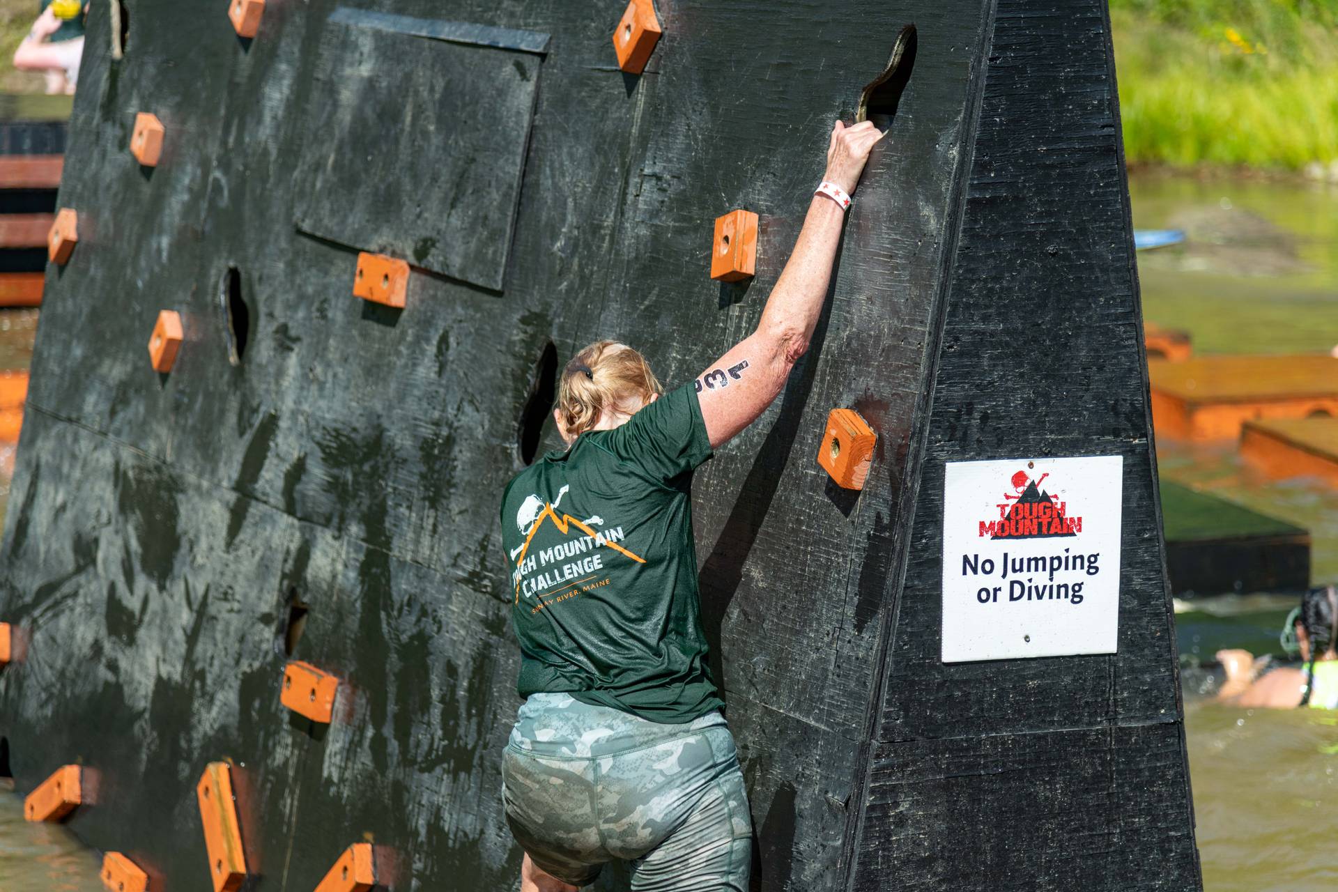 A woman doing a rock climb at Tough Mountain Challenge.