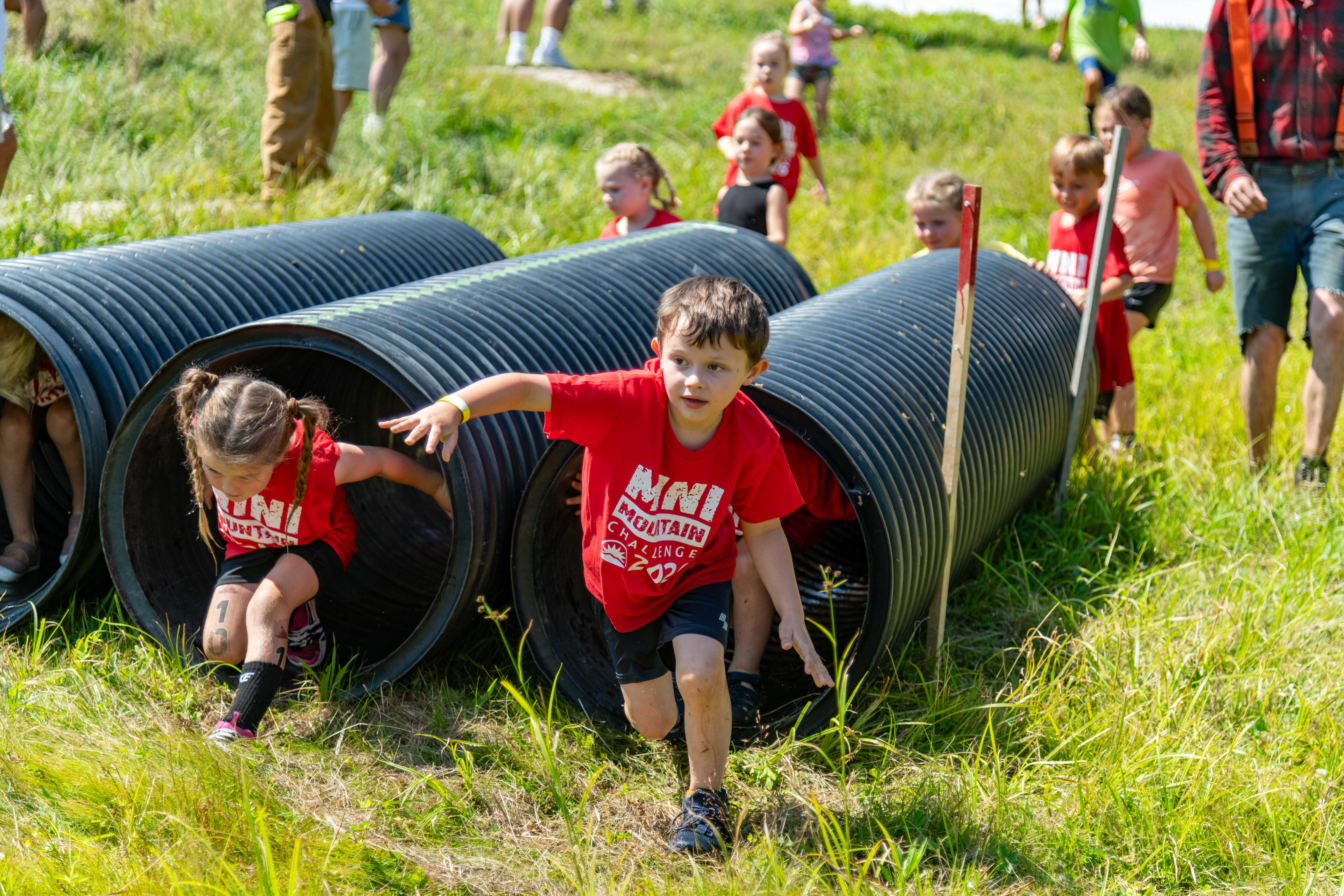 Kids crawling out a tunnel.