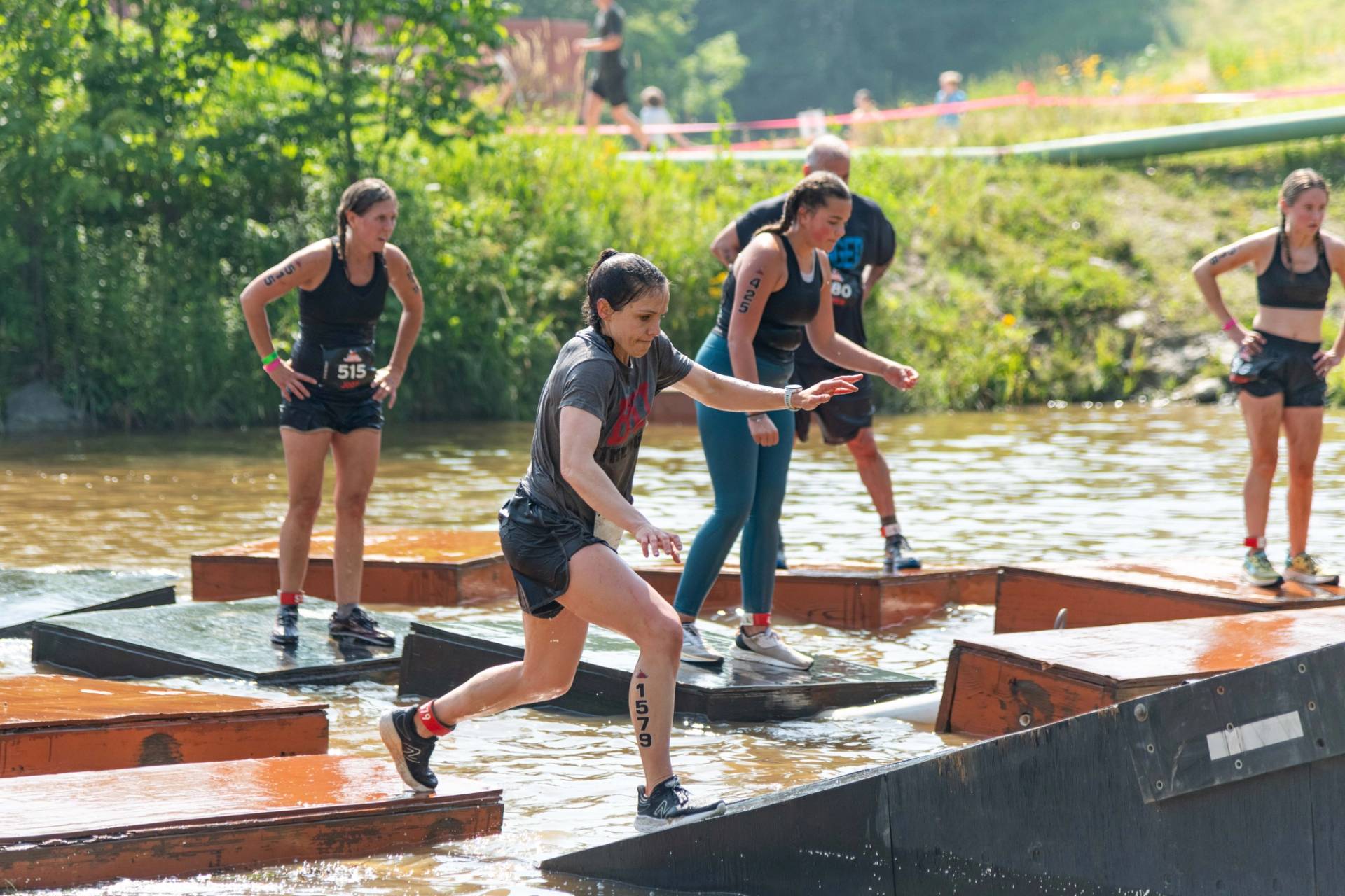 People running through a water obstacle Sunday River's Tough Mountain Challenge.