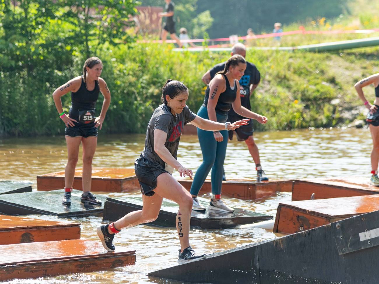 A runner jumping on the pontoon platforms through the pond.