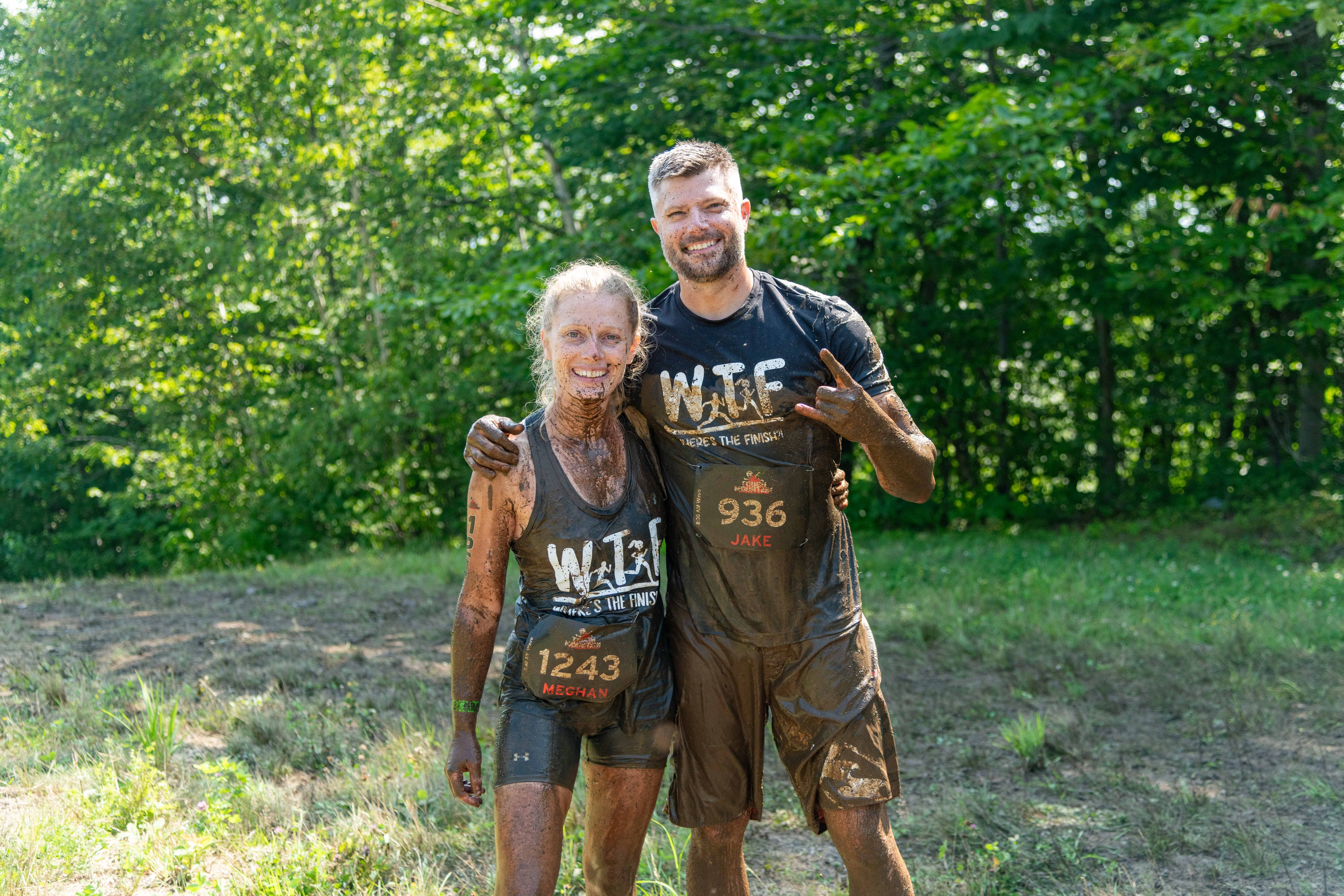 Competitors hugging covered in mud at the Tough Mountain Challenge.