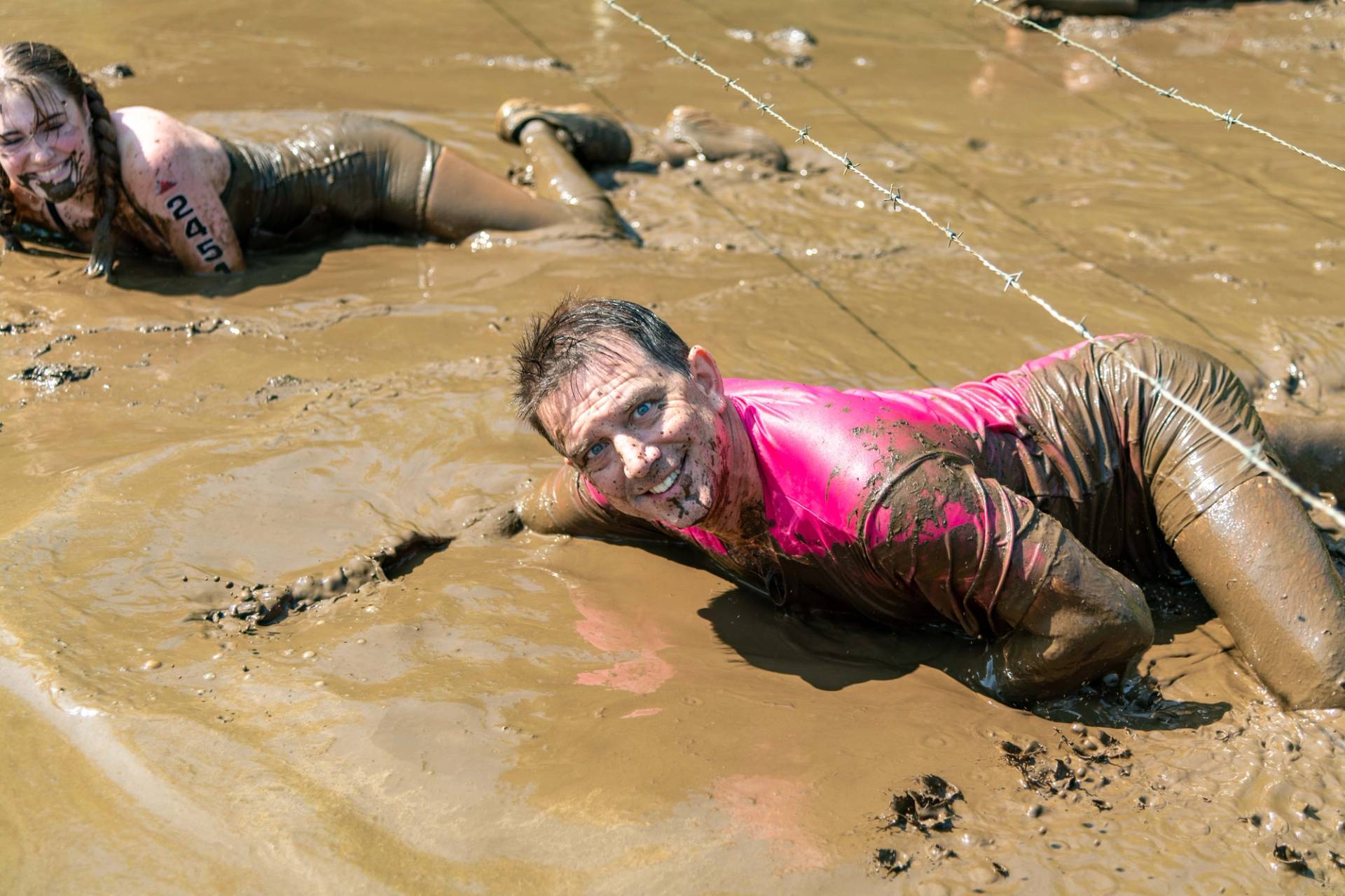 A guy crawling through the mud at Sunday River's Tough Mountain Challenge.