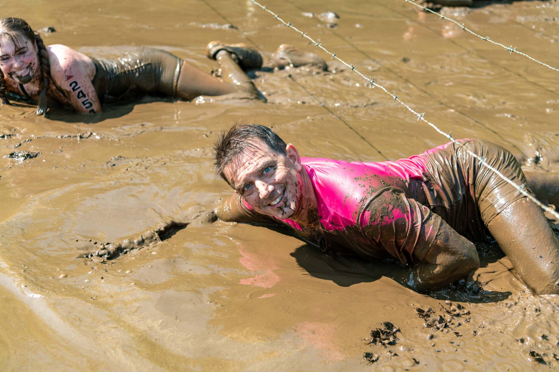 A guy crawling through the mud at Sunday River's Tough Mountain Challenge.