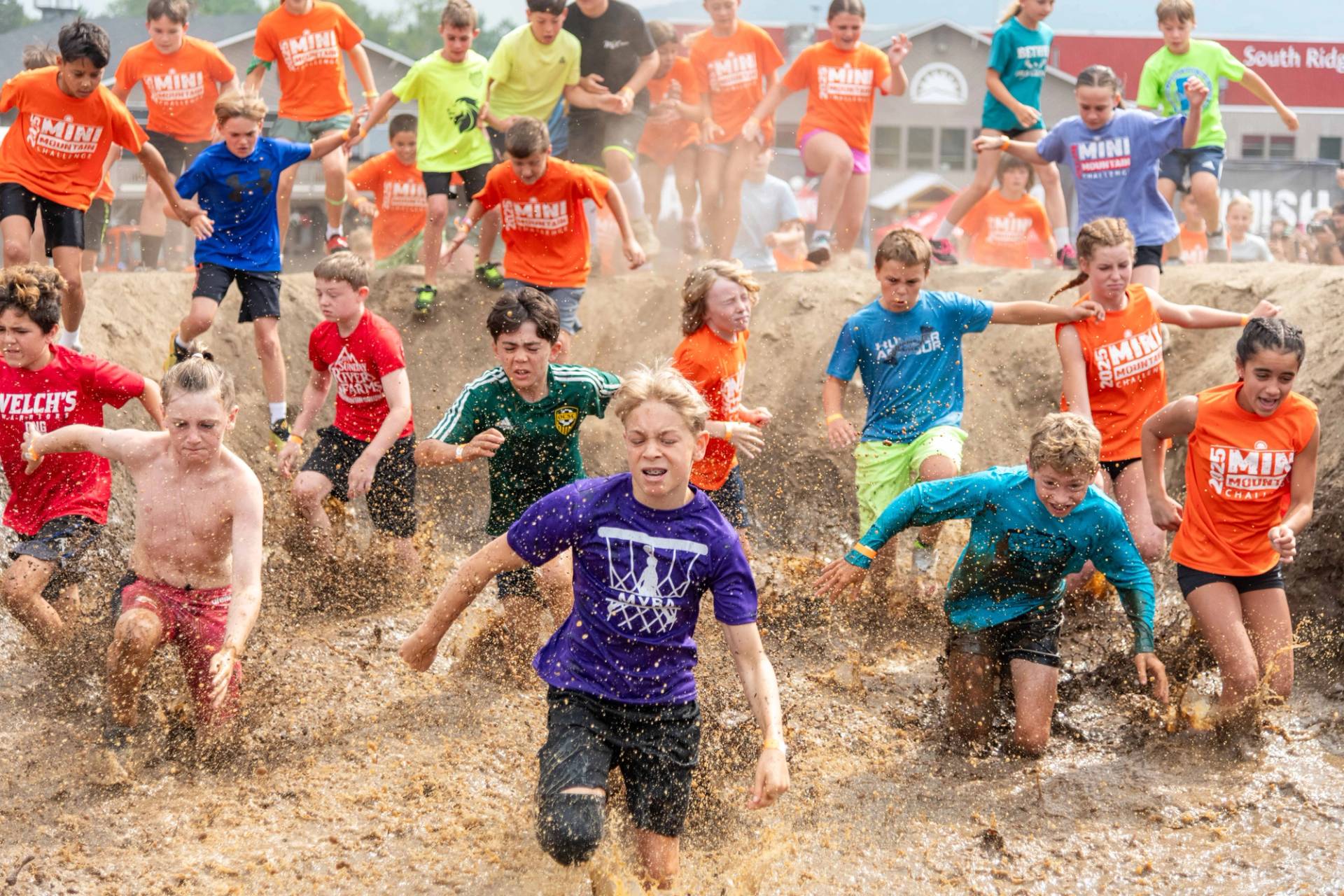 People running through a water obstacle Sunday River's Tough Mountain Challenge.