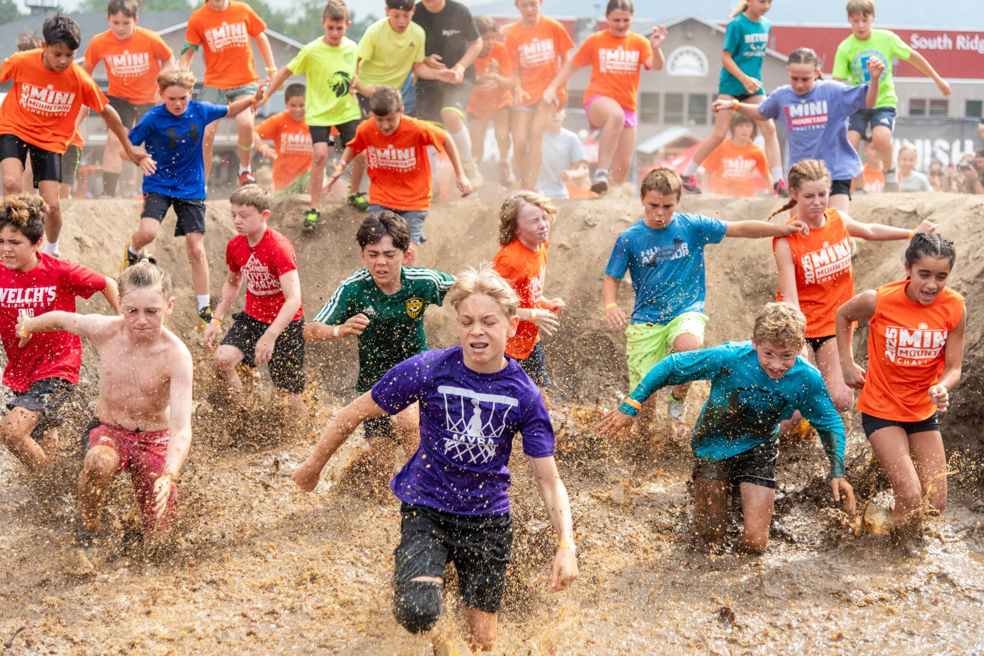 People running through a water obstacle Sunday River's Tough Mountain Challenge.
