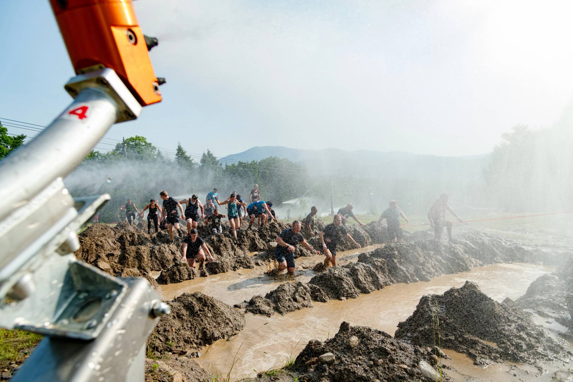 Athletes jumping through muddy pits at Sunday River's Tough Mountain Challenge.