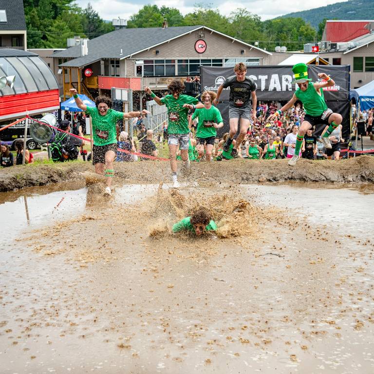 Kids jumping into the mud pit at the Tough Mountain Challenge at Sunday River.