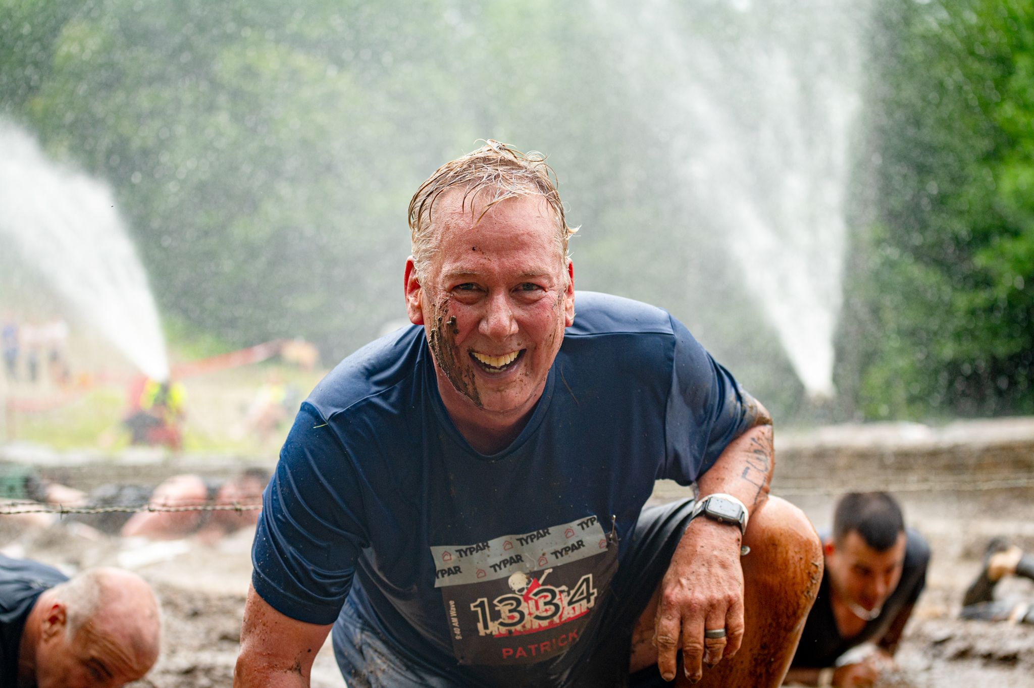 A Tough Mountain Challenge participant emerges from an obstacle with a smile.