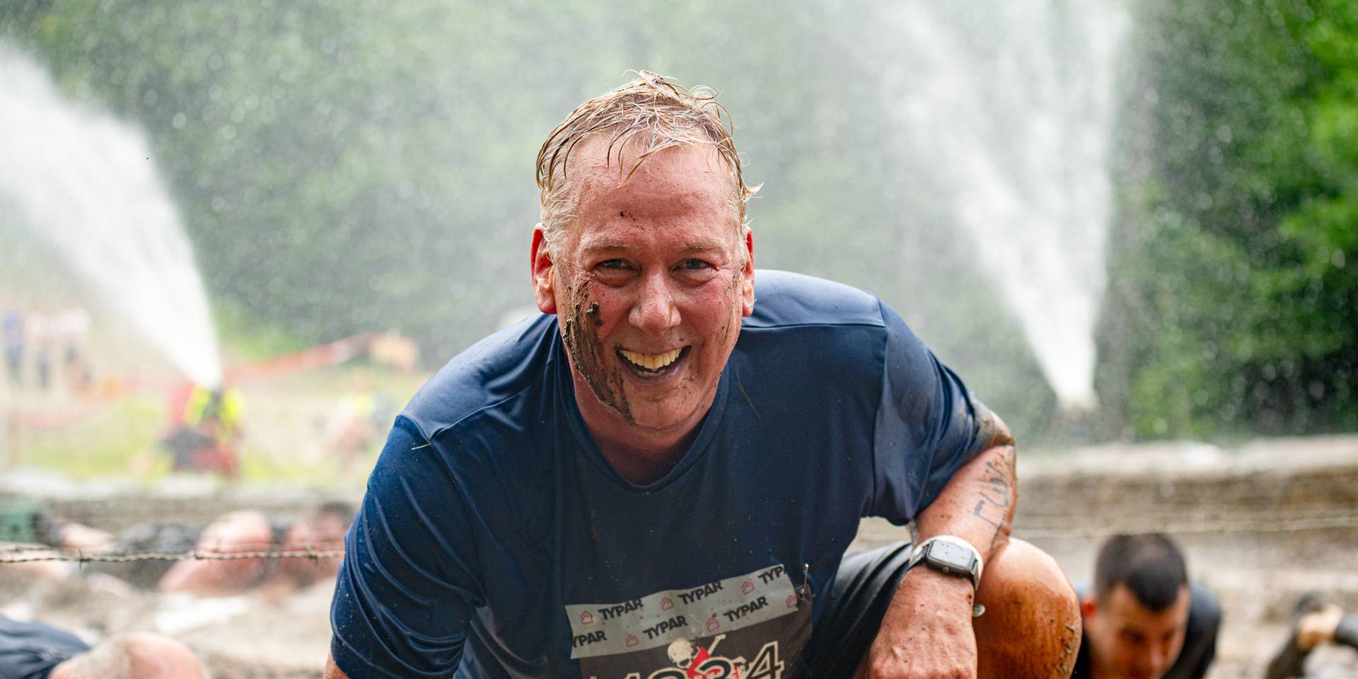 A Tough Mountain Challenge participant emerges from an obstacle with a smile.