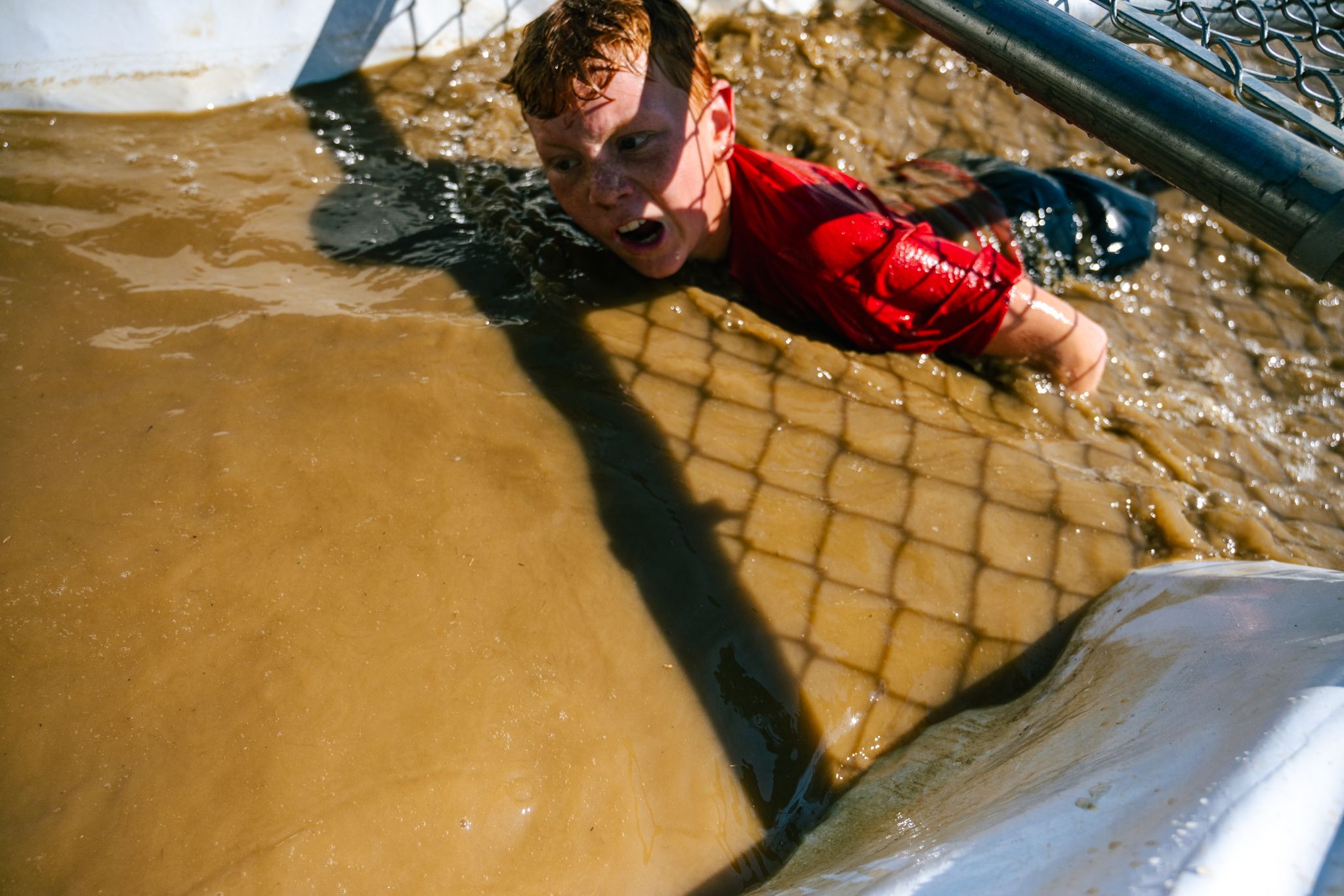 A little boy going under a fence in an obstacle at Mini Mountain Challenge.