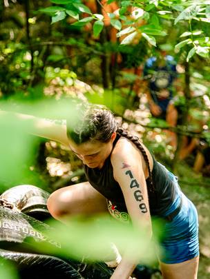 A woman climbing a tire wall at Sunday River's Tough Mountain Challenge.
