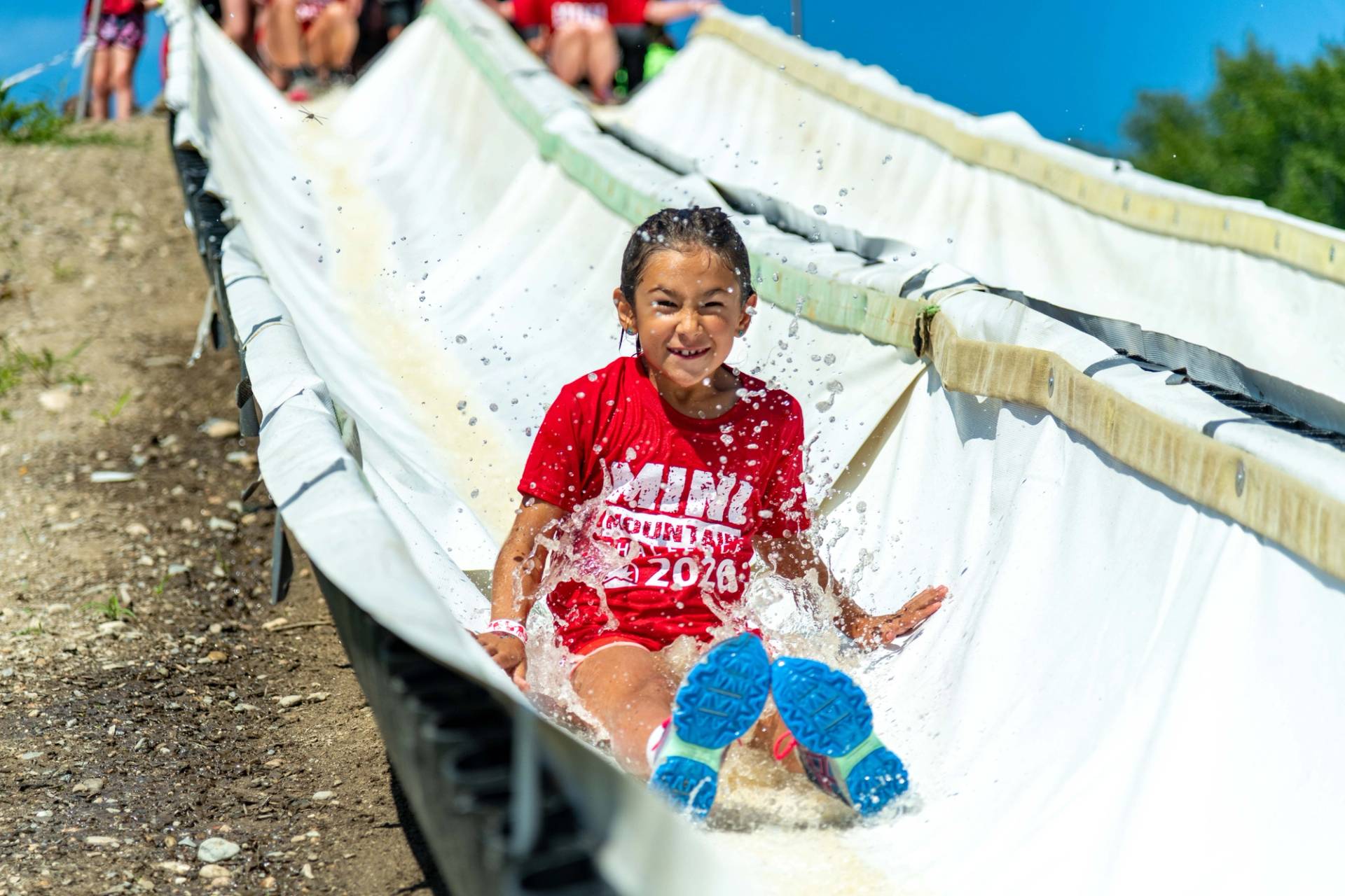Mini Mountain challenge participant going down a waterslide.