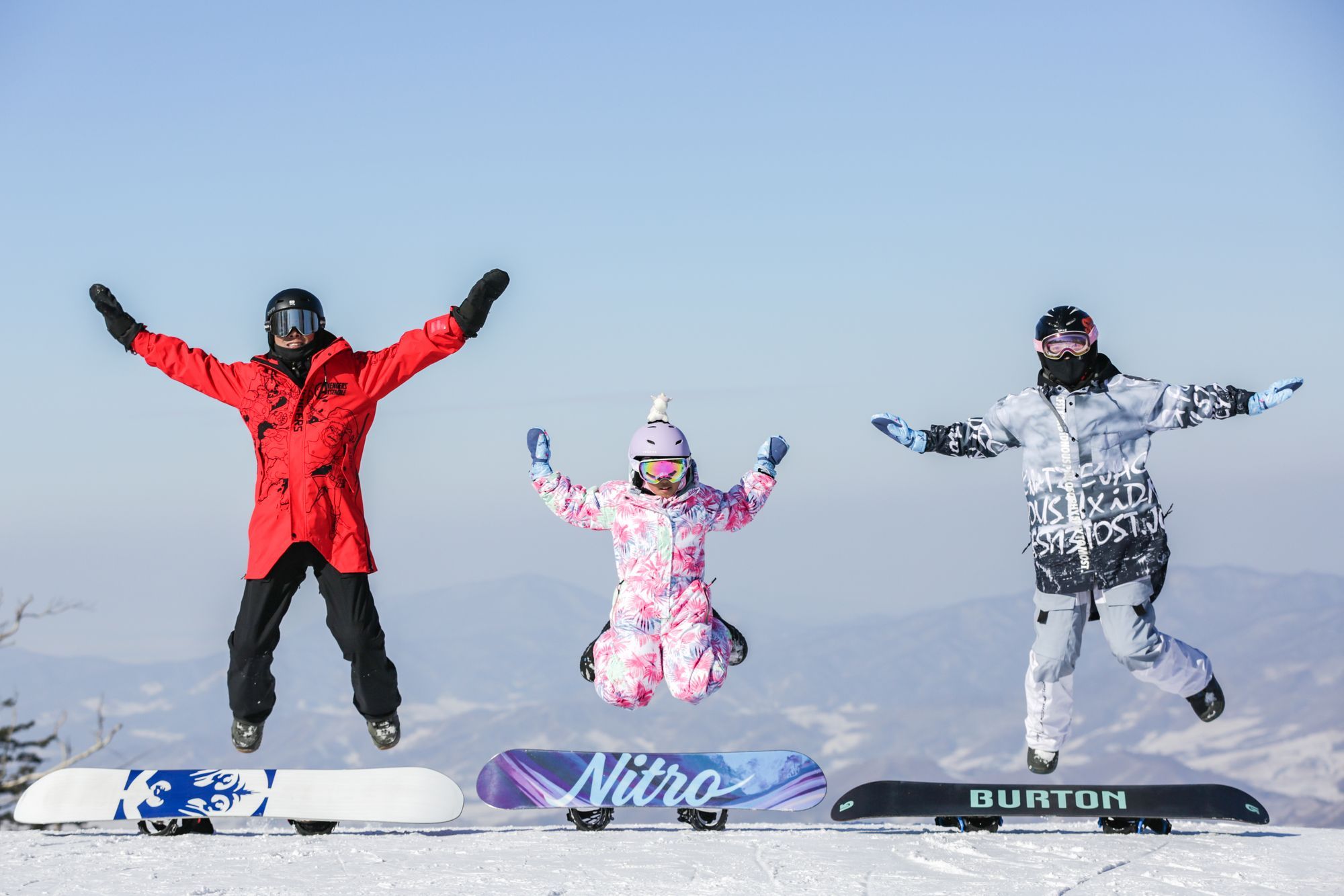 family jumping above snowboards