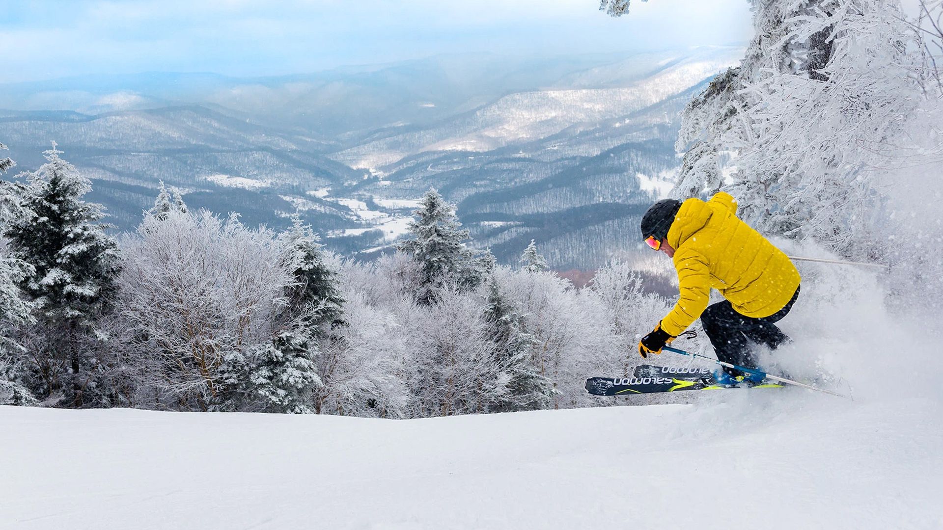 Skier catching air while carving down a snowy slope with fresh powder.
