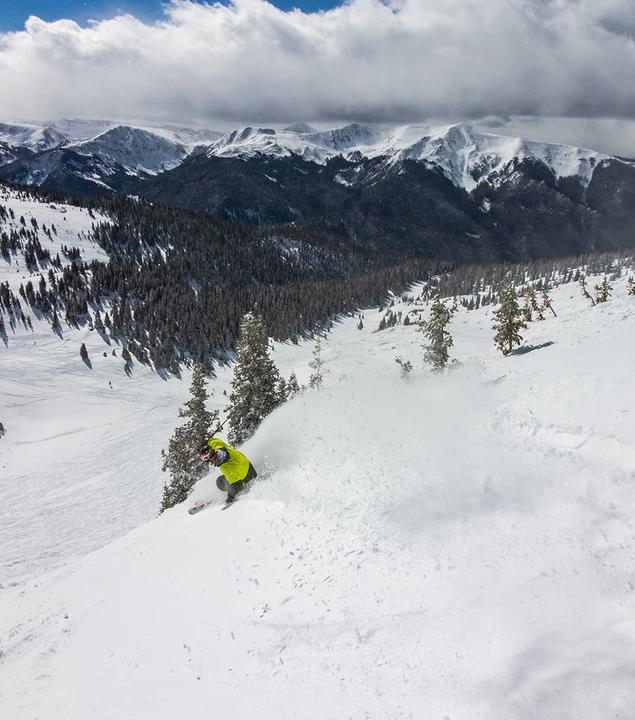 Skier descending a mountain covered in powdery snow.