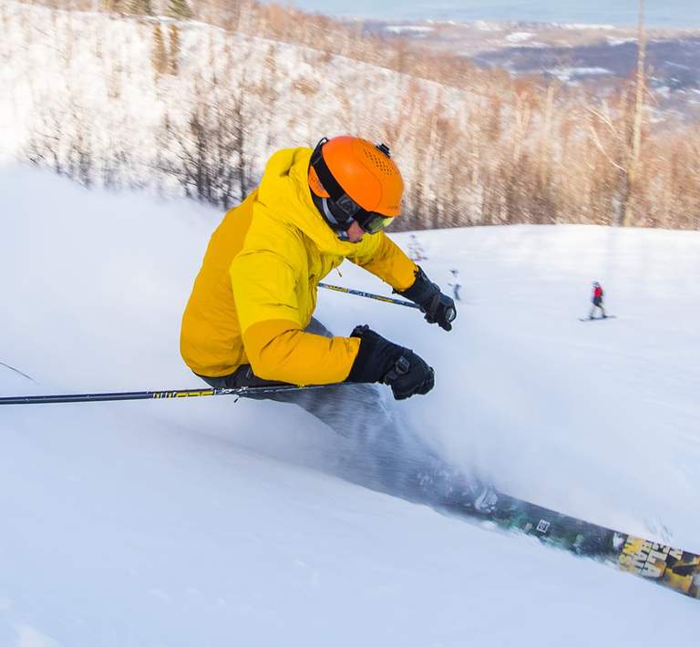 Action shot of skier leaving a cloud of powder behind as they navigate downhill.