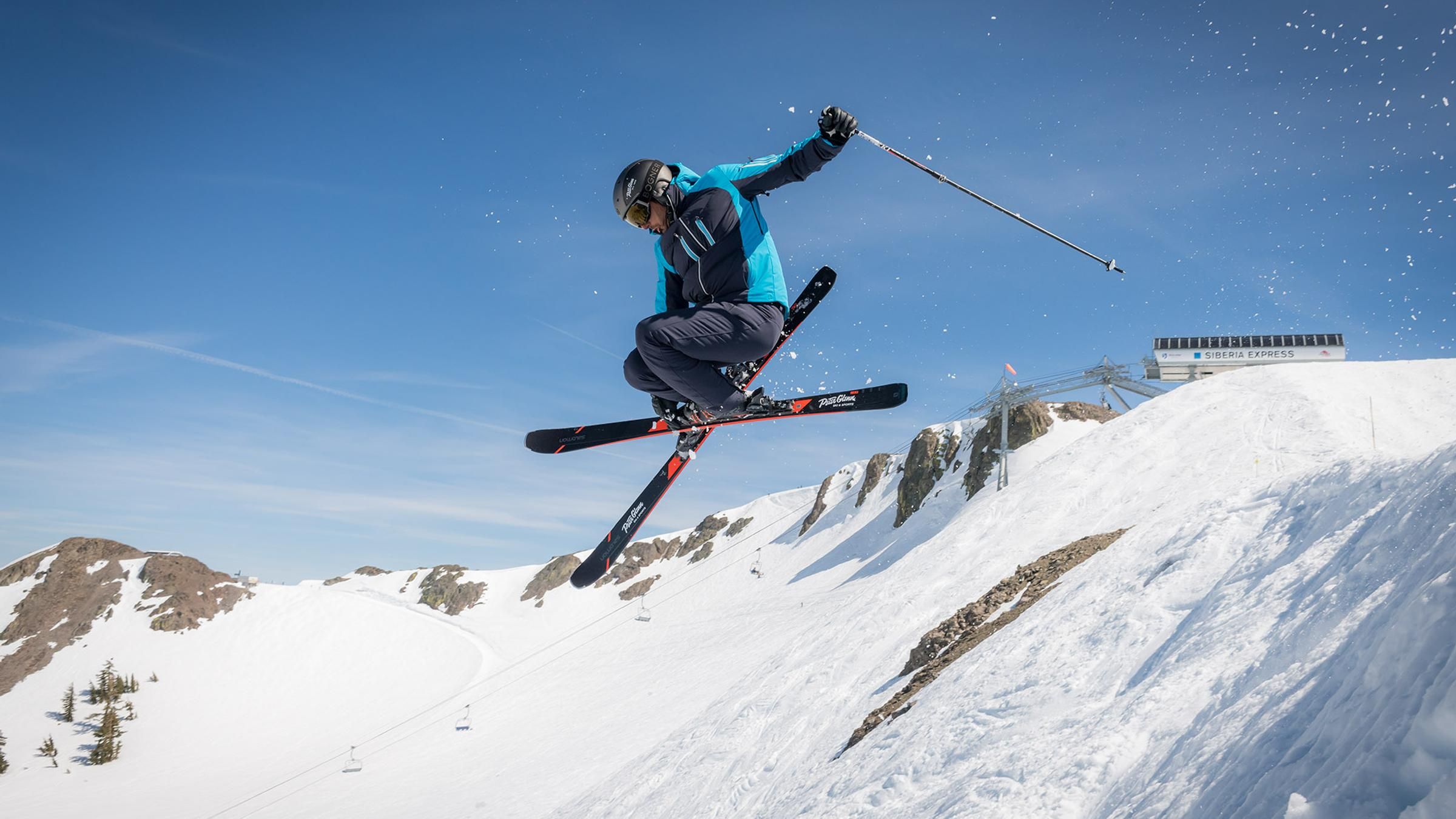 Skier jumping in the air off a snowy ridge