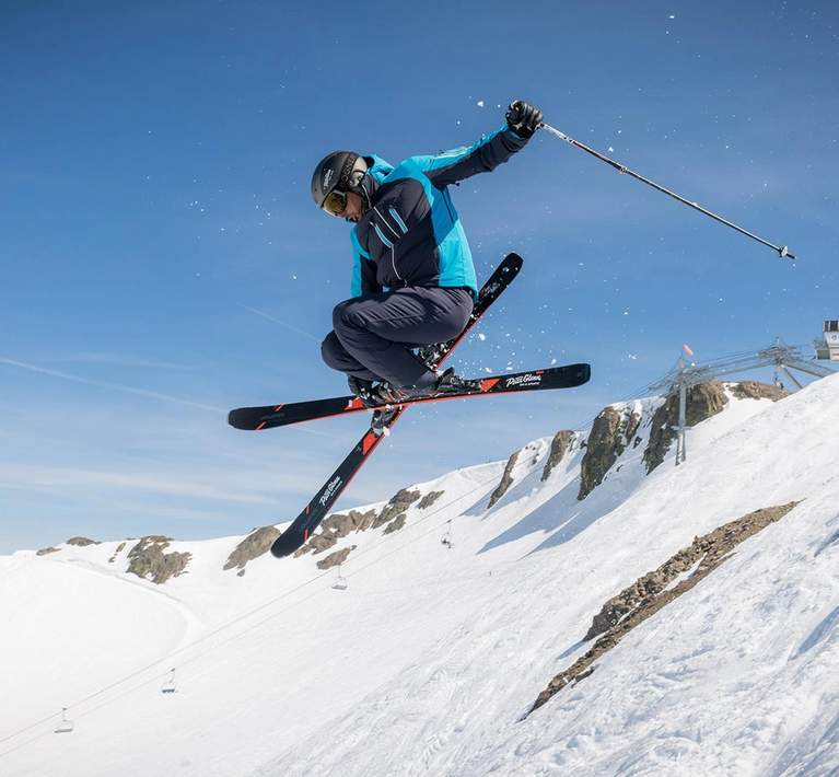 Skier jumping in the air off a snowy ridge