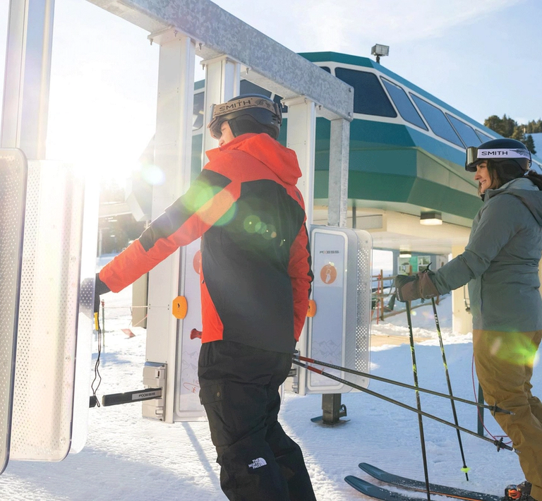 A male and female skier getting ready to go through the RFID gates to head towards the chairlifts at Snow Summit
