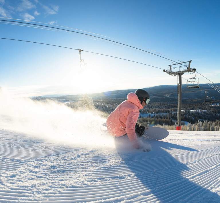 Snowboarder going down a groomed run